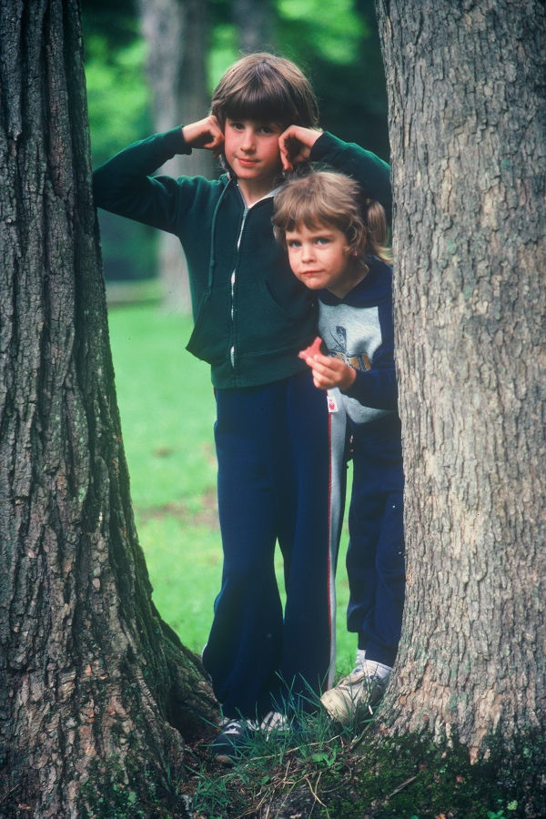 David Bott's daughters, Rachelle (Bott) Beckner and Sara Bott peer between the pine trees at Cabin 20 near the swimming pool. | 📸: Leonard Bott