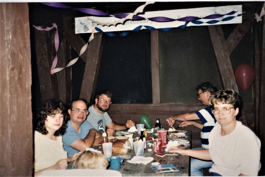 We are celebrating my parents’ wedding anniversary on August 19, 1988 in Cabin 14 at Watoga. From L-R, foreground to background: Joanna Joseph Reynolds, my cousin, in highchair; Aunt Barbara Bott Joseph; Uncle Bob Joseph, my dad, David Bott, across from him Grandpa Bott (Leonard S. Bott); and my mom, Donna Bott. 📸: Rachelle Bott Beckner.Rachelle Bott Beckner.