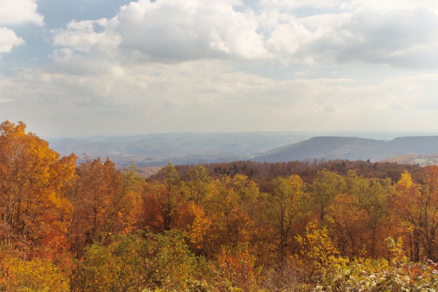 Hues of orange red and yellow highlight the foreground of TM Cheek Memorial Overlook where you can see Kennison Mountain and the Greenbrier River Valley in the distance. Always worth a photo no matter the season is the overlook at T.M. Cheek Memorial. Photo by Stanley©.