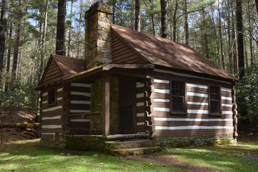 A log cabin build by the Civilian Conservation Corp in the early 1930s is nestled neatly again a backdrop of tall tress as spring and green begins to emerge in 2021. Cabin 34 - the "Honeymoon Cabin," is a Top 10 choice for newlyweds. 📸: John C. Dean