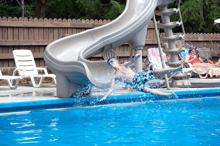 A nice summer day greets a young visitor as he slides down the slide. Youngsters always list the pool in their Top 10. The swimming pool is a popular spot on the 4th of July at Watoga. Photo by Stanley Clark©.